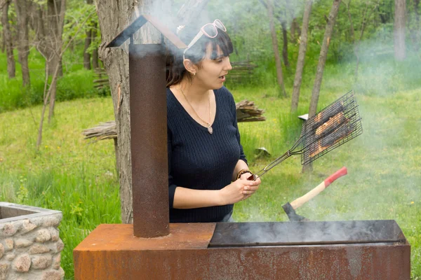 Belle femme cuisinant de la viande sur un barbecue — Photo