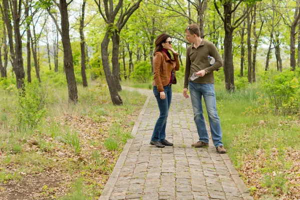 Pareja joven de pie hablando en un parque —  Fotos de Stock