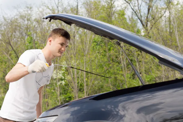 Молодий чоловік перевіряє моторну олію автомобіля — стокове фото