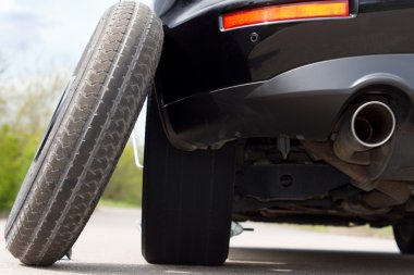 Spare tyre balanced against a car clipart