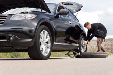 Young man with a roadside puncture clipart