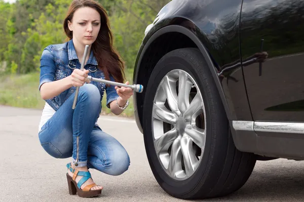 Confused woman looking at a wheel spanner — Stock Photo, Image
