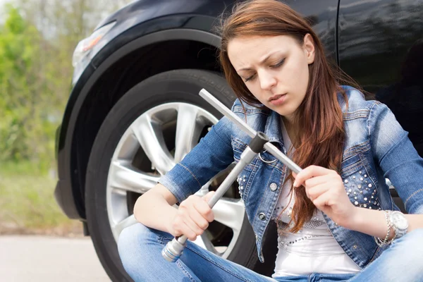 Ignorant woman frowning at a wheel spanner — Stock Photo, Image