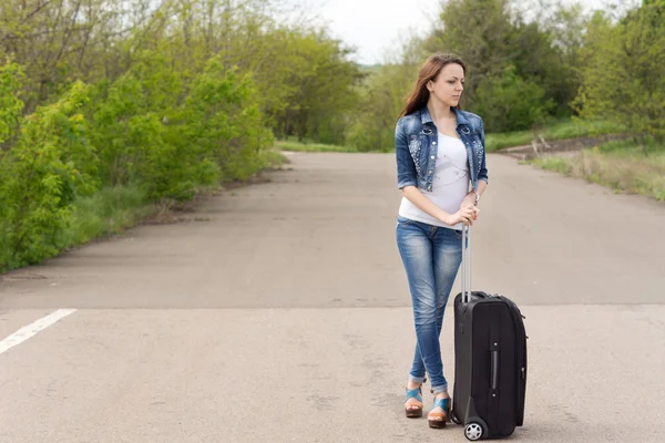 Mujer esperando con su maleta en el camino —  Fotos de Stock