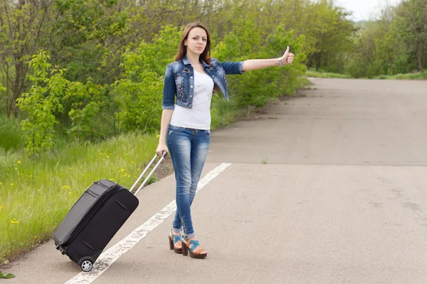 Молода жінка тримає візок під час автостопу — стокове фото