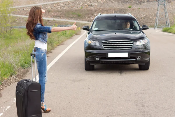 Woman hitchhiking after a breakdown with her car — Stock Photo, Image