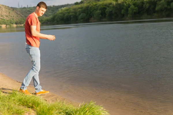 Handsome young man beside a calm lake — Stock Photo, Image