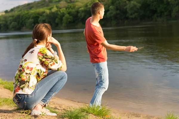 Young man skimming stones across water — Stock Photo, Image