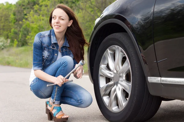 Smiling young woman getting ready to change a tyre Stock Image