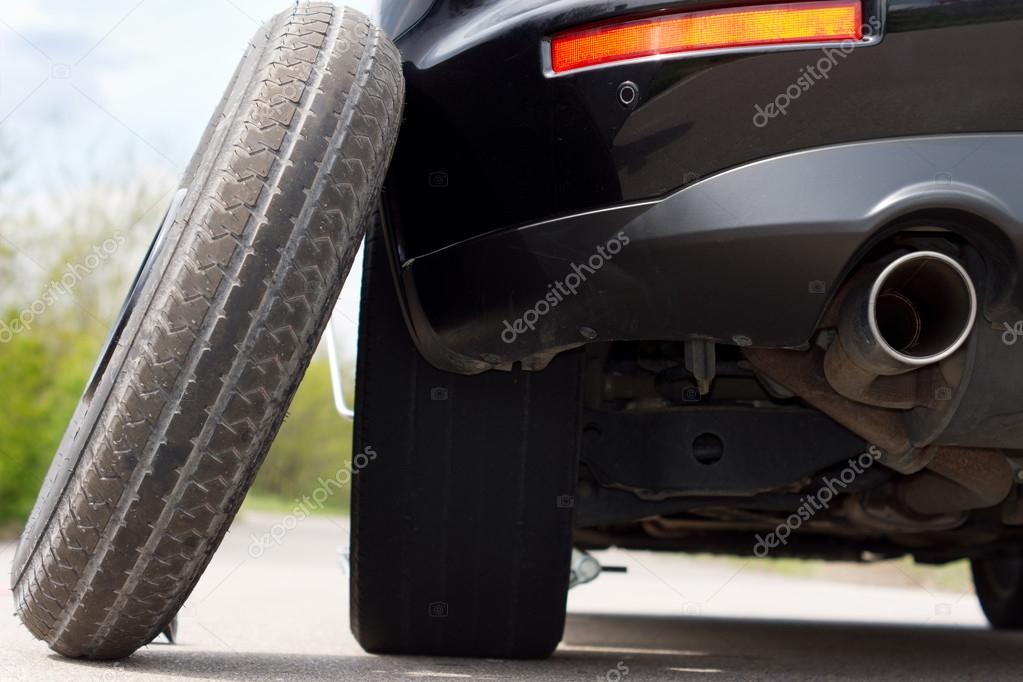 Spare tyre balanced against a car