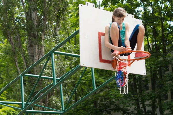 Chica joven ágil fijando una red en un gol de baloncesto — Foto de Stock