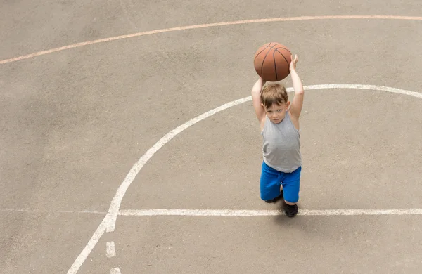 Petit garçon jouant sur un terrain de basket — Photo