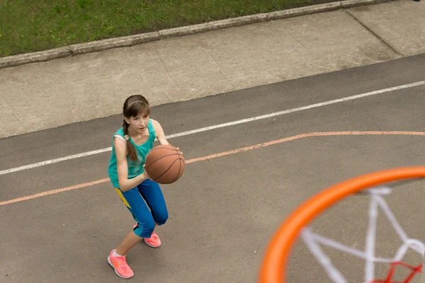 Dospívající dívka hází basketbal na netu — Stock fotografie