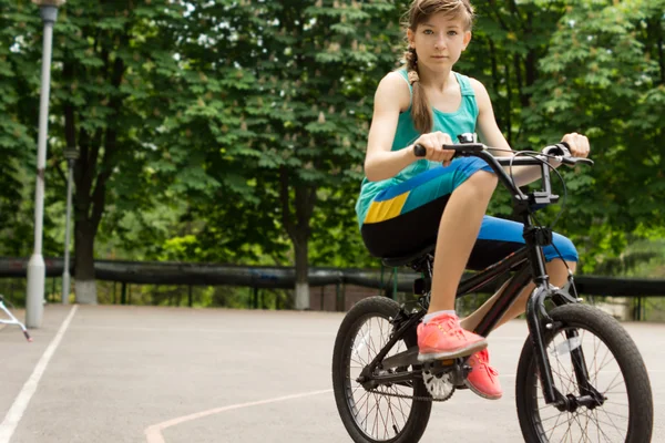 Дівчина-підліток їде позичений дитячий велосипед — стокове фото