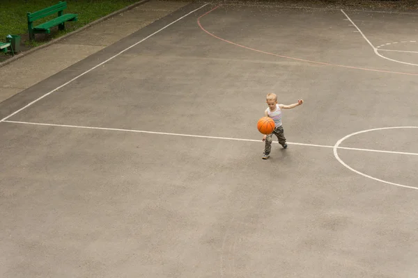 Liten pojke spela basket studsa bollen — Stockfoto