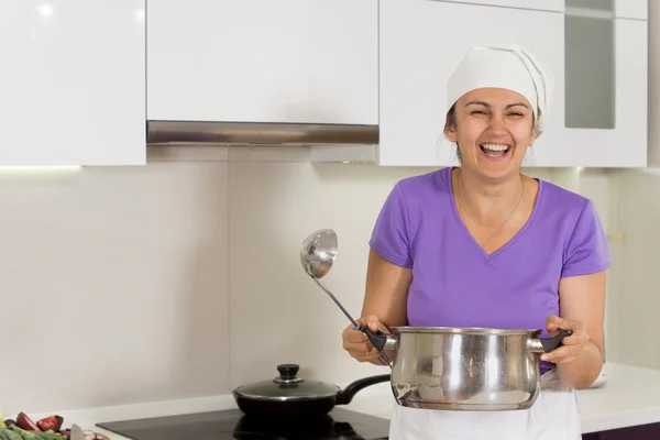 Laughing cook holding a big metal saucepan — Stock Photo, Image