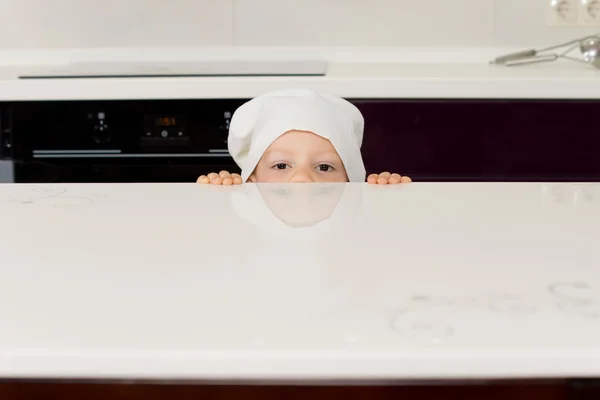 Junge mit Kochmütze guckt über den Ladentisch — Stockfoto