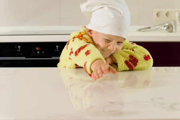 Criança pequena que se estende através de um balcão de cozinha — Fotografia de Stock