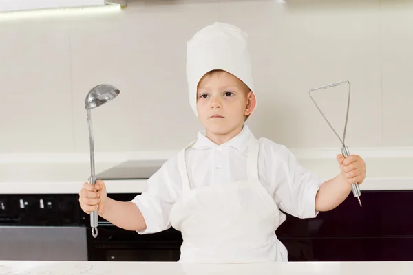 Stolzer kleiner Junge Koch hält seine Utensilien hoch — Stockfoto