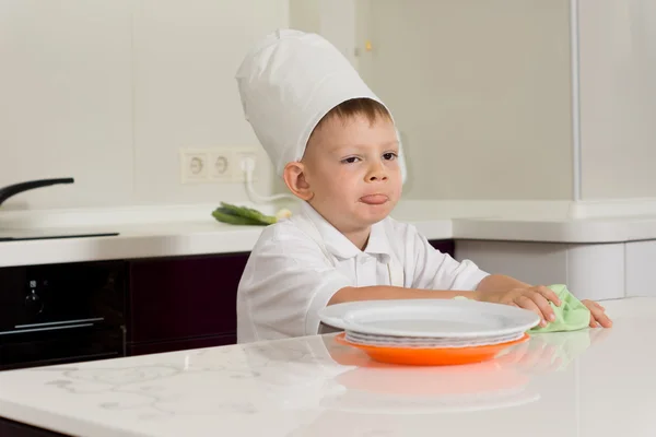 Pequeno chef bonito limpando o balcão da cozinha — Fotografia de Stock