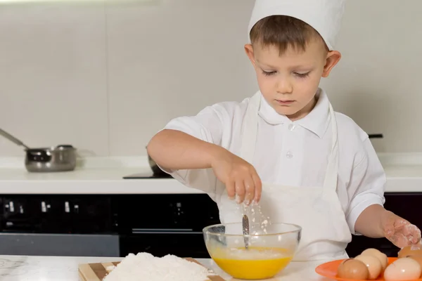 Jeune garçon casser des œufs dans un bol de mélange — Photo