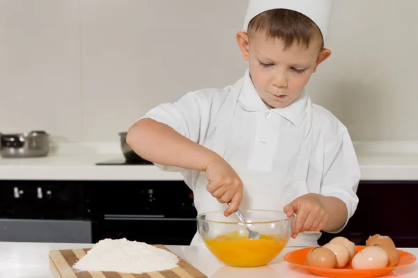 Joven niño batiendo huevos con un tenedor — Foto de Stock