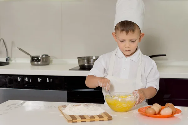 Kleiner Junge steht beim Kuchenbacken in einer Haube — Stockfoto