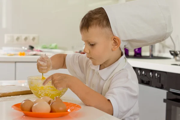 Cute young boy chef whipping the eggs — Stock Photo, Image