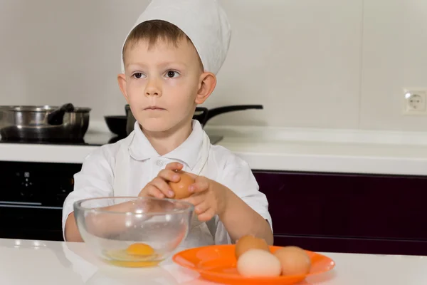 Young chef breaking eggs into bowl — Stock Photo, Image