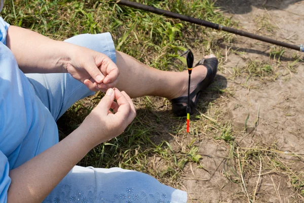 Mujer enhebrando cebo en su anzuelo mientras pesca —  Fotos de Stock