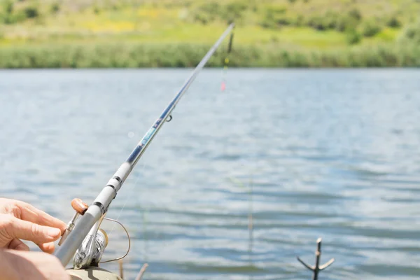 Homem de pesca em um lago com um carretel de fiação e haste — Fotografia de Stock