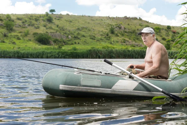 Homme âgé pêche à partir d'un canot en caoutchouc — Photo