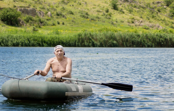 Пожилой рыбак гребёт через озеро
