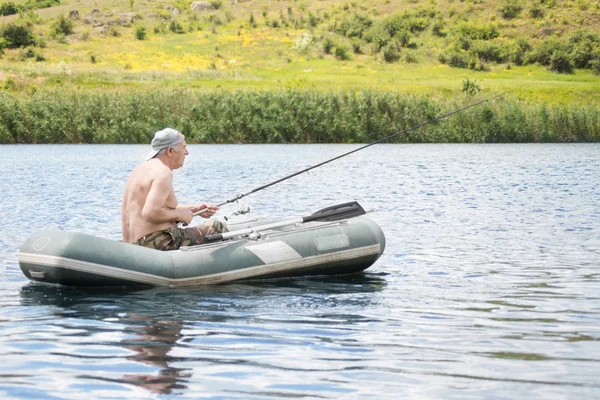 Senior mens vissen vanaf een rubberboot in een meer — Stockfoto