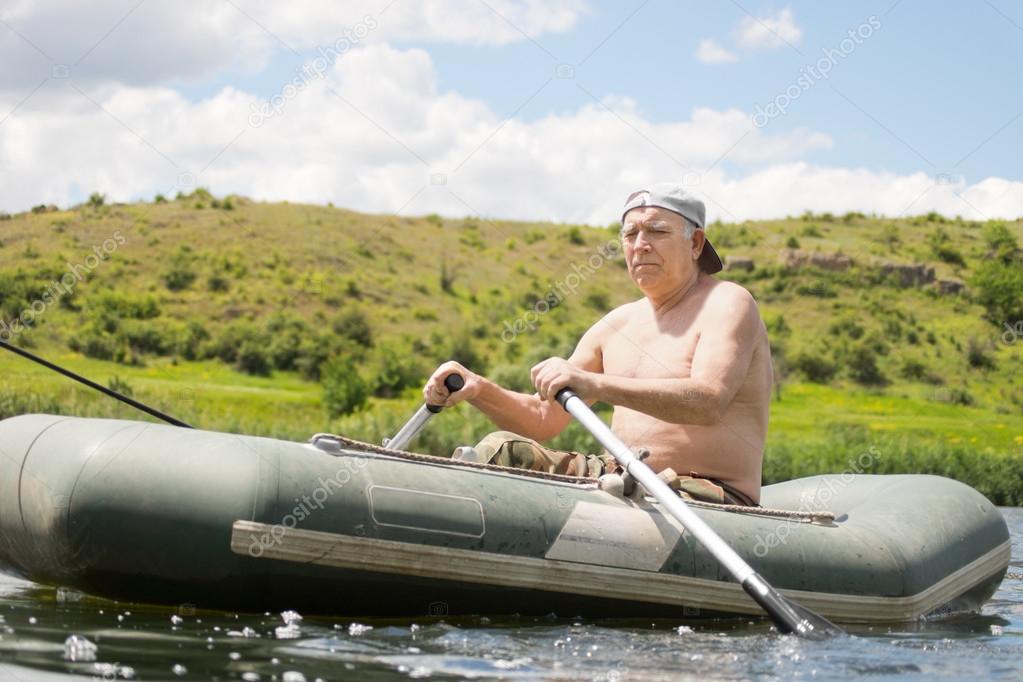 Senior man rowing an inflatable dinghy on a lake