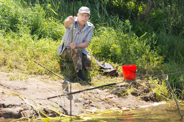 Old fisherman by the riverbank fishing — Stock Photo, Image