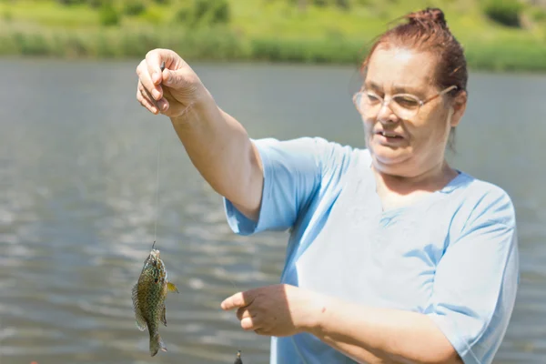 Old woman holding her catch — Stock Photo, Image