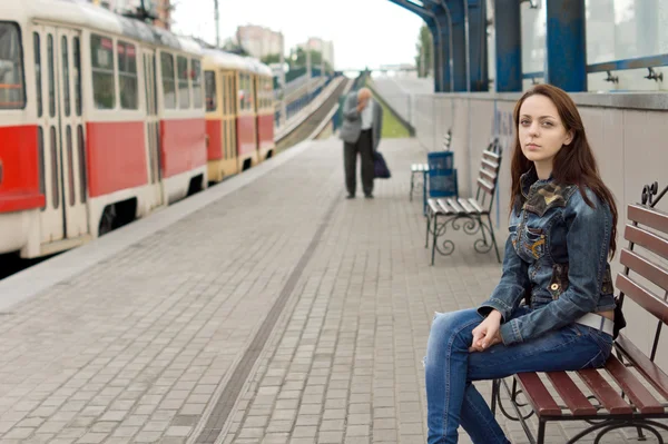 Žena sedí na lavičce v železniční stanici — Stock fotografie