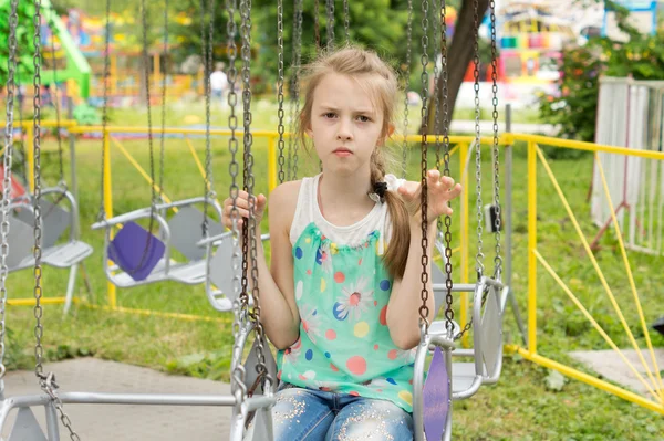 Menina sentada na cadeira de um carrossel swing — Fotografia de Stock