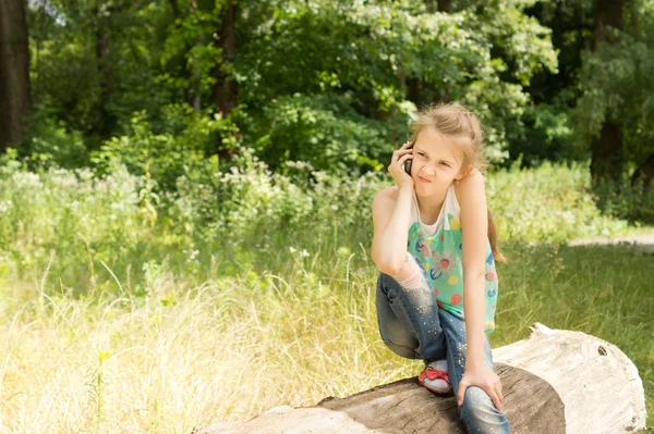 Liten flicka sitter på en logg tänkande — Stockfoto