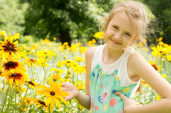 Leende ung flicka spelar i gula blommor — Stockfoto