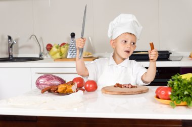 Little boy wielding a large knife in the kitchen clipart