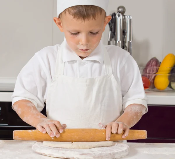 Young boy in chefs uniform rolling dough — Stock Photo, Image