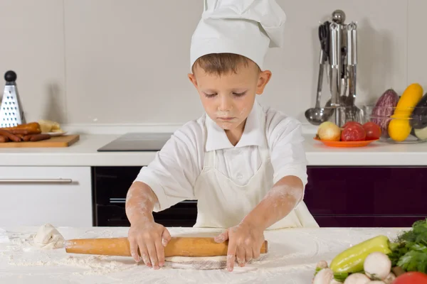 Petit garçon déroulant la pâte dans la cuisine — Photo