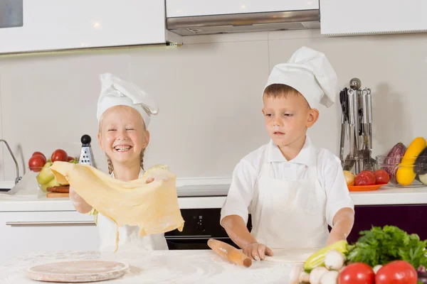 Двое маленьких детей веселятся, делая пиццу — стоковое фото