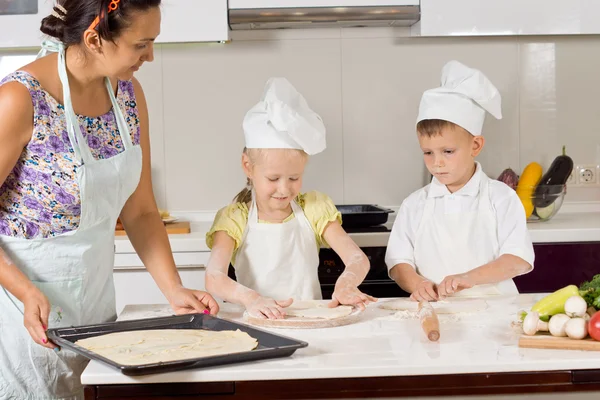 Kinder helfen ihrer Mutter bei der Teigzubereitung — Stockfoto