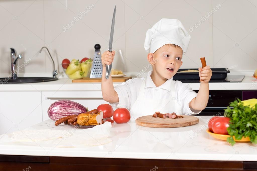 Little boy wielding a large knife in the kitchen