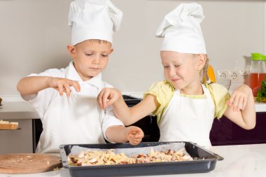 sevimli küçük çocuk şefler malzemelerle pizza üzerine koyarak