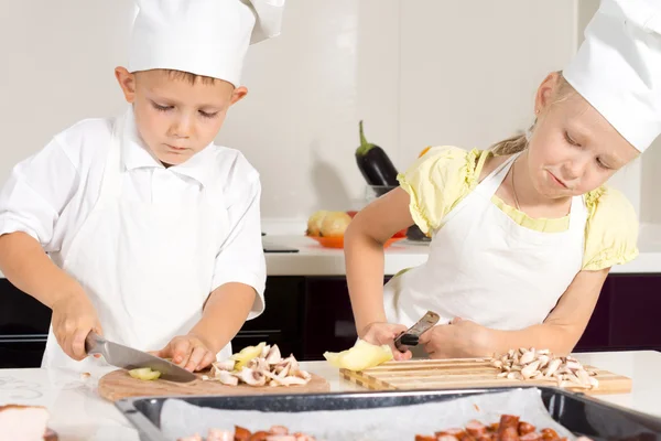 Chefs de niños rebanando ingredientes en la tabla de cortar —  Fotos de Stock