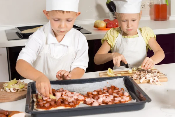 Söta lilla barn i kocken klädsel att göra pizza — Stockfoto